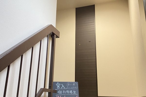 塾の入口から見上げる落ち着いた階段と案内板